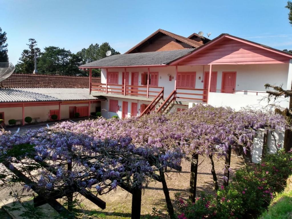 una casa con flores púrpuras delante de ella en Apartamentos Aromas de Gramado - Bairro Centro en Gramado