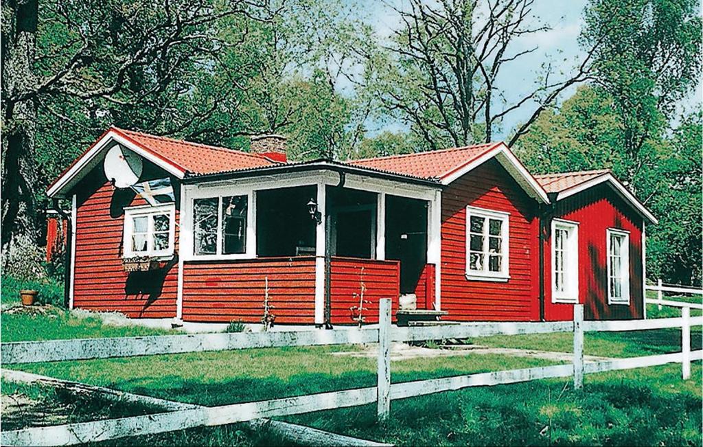 une petite maison rouge avec une clôture en bois dans l'établissement 2 Bedroom Awesome Home In Ljungsarp, à Ljungsarp