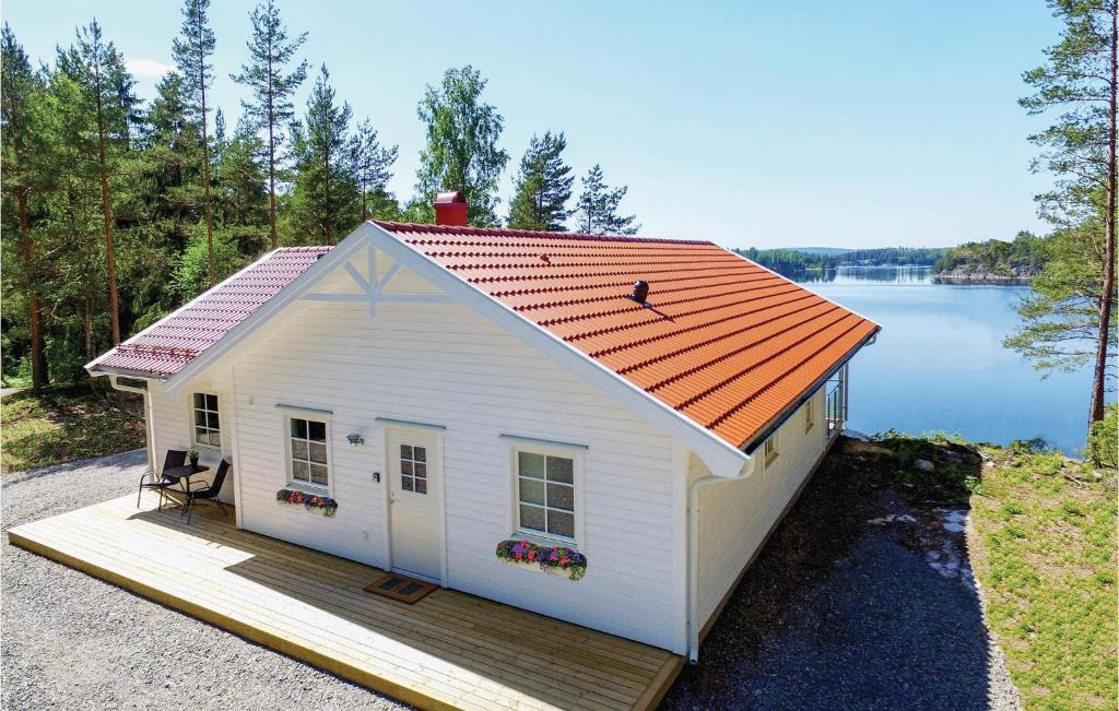 uma pequena casa branca com um telhado laranja numa doca em Gorgeous Home In rjng With Wifi em Östra Viker