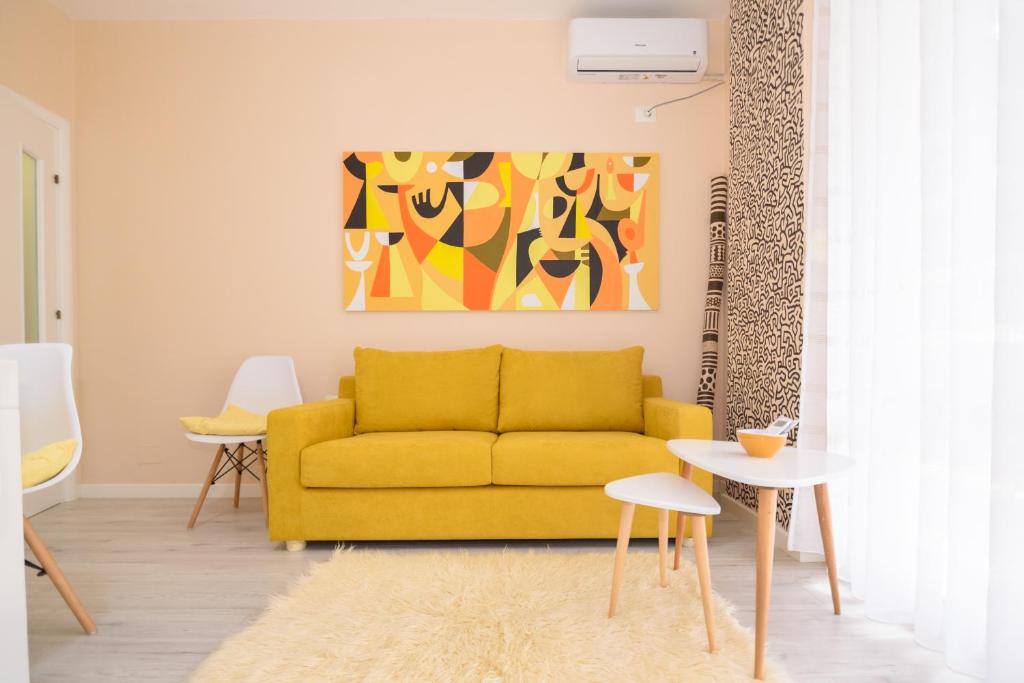 a yellow couch in a living room with a painting at Lovely apartment Lungomare in Vlorë