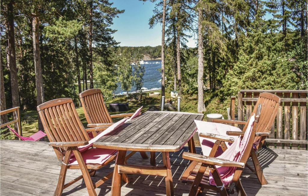 a wooden table and chairs on a deck with trees at Cozy Home In Djurhamn With Wifi in Djurhamn
