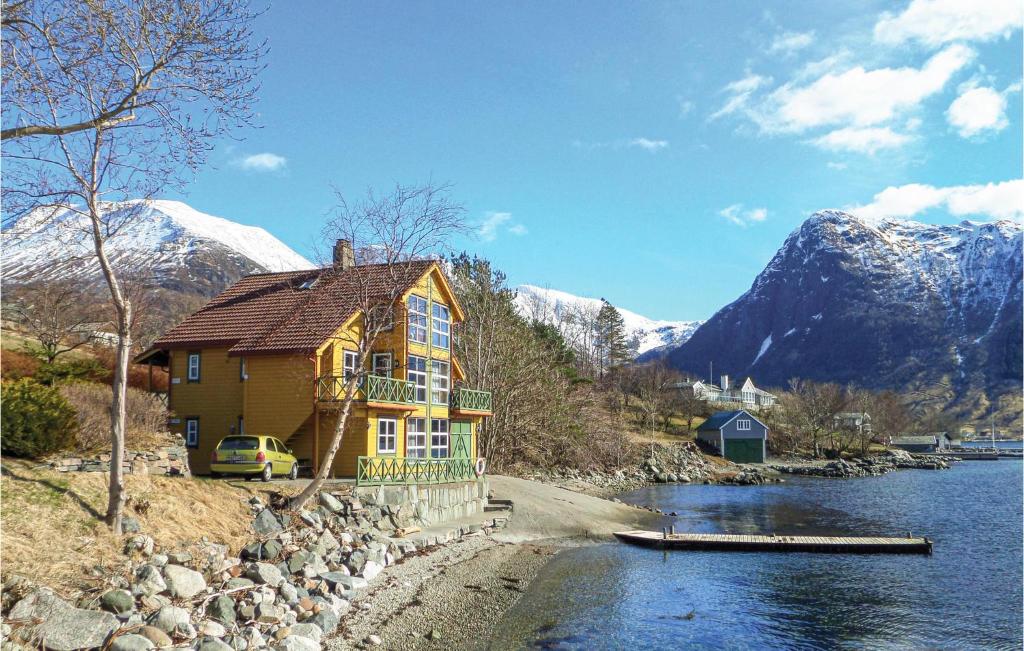 una casa gialla sul lato di un fiume con montagne di 2 Bedroom Pet Friendly Apartment In Rosendal a Rosendal