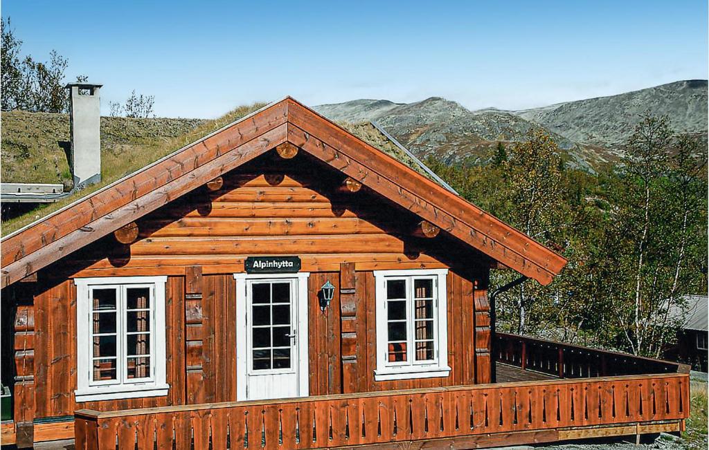 a wooden cabin with white windows and mountains in the background at Lovely Home In Hemsedal With Wifi in Hemsedal