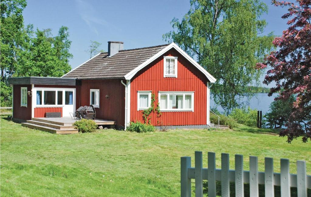 une maison rouge dans un champ avec une clôture dans l'établissement Awesome Home In Vrnamo With Kitchen, à Värnamo