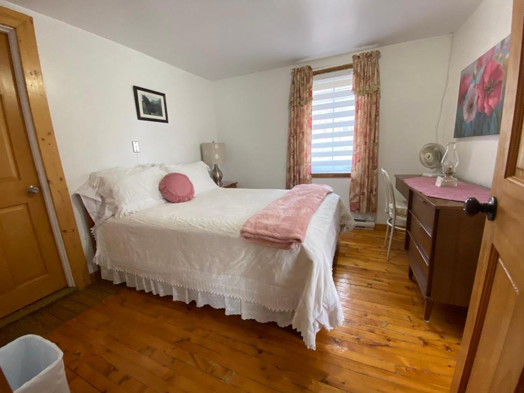 een slaapkamer met een bed, een dressoir en een raam bij gite cap a l aigle in La Malbaie