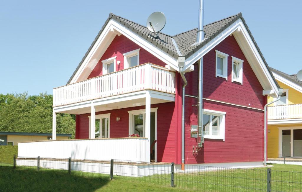 ein rotes Haus mit einer weißen Veranda in der Unterkunft Seerose 8 in Süssau