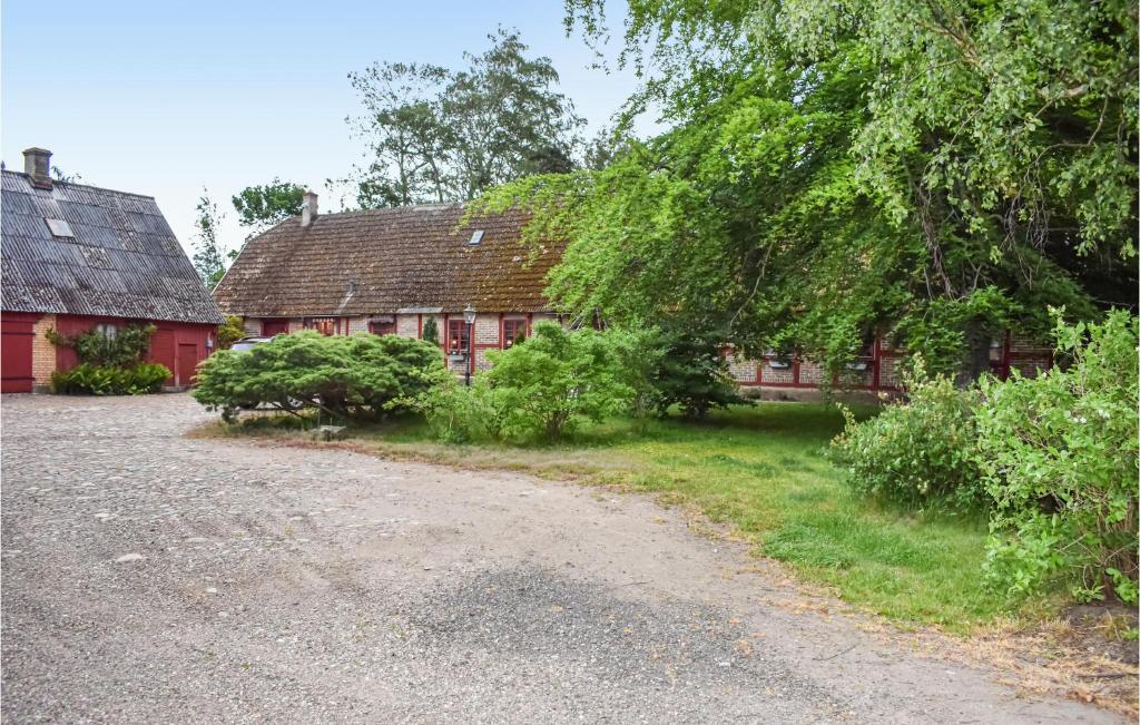 a red barn with a dirt road in front of it at Lovely Home In Annelv With Kitchen in Annelöv