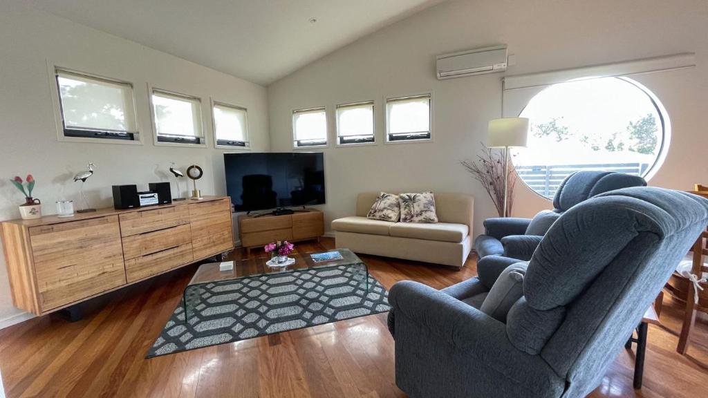 a living room with two chairs and a flat screen tv at Romantic Retreat Inverloch in Inverloch