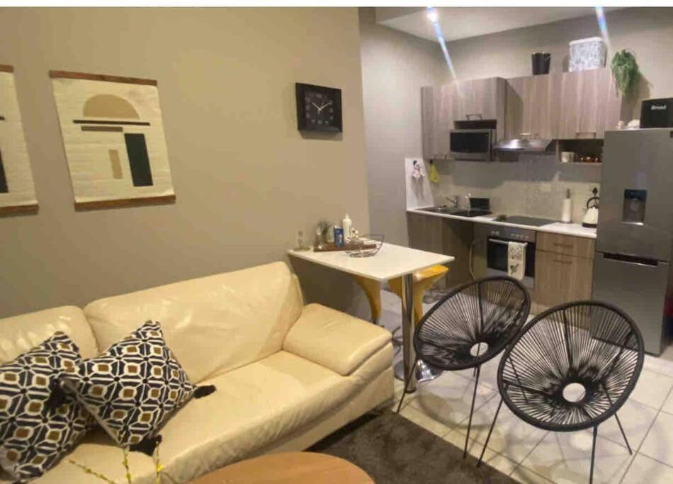 a living room with a couch and a table and a kitchen at Stylish Dante’s 1-bedroom condo free Wifi & Cinema in Johannesburg