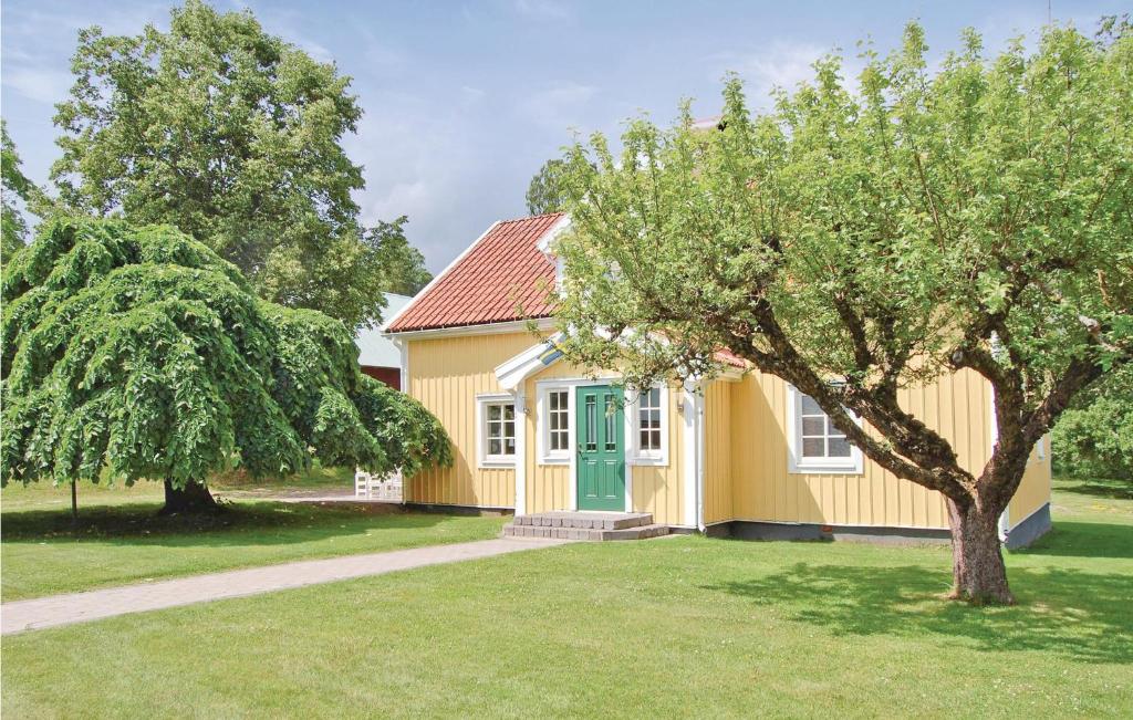 une maison jaune avec une porte verte et un arbre dans l'établissement Awesome Home In Vimmerby With 5 Bedrooms And Wifi, à Flohult