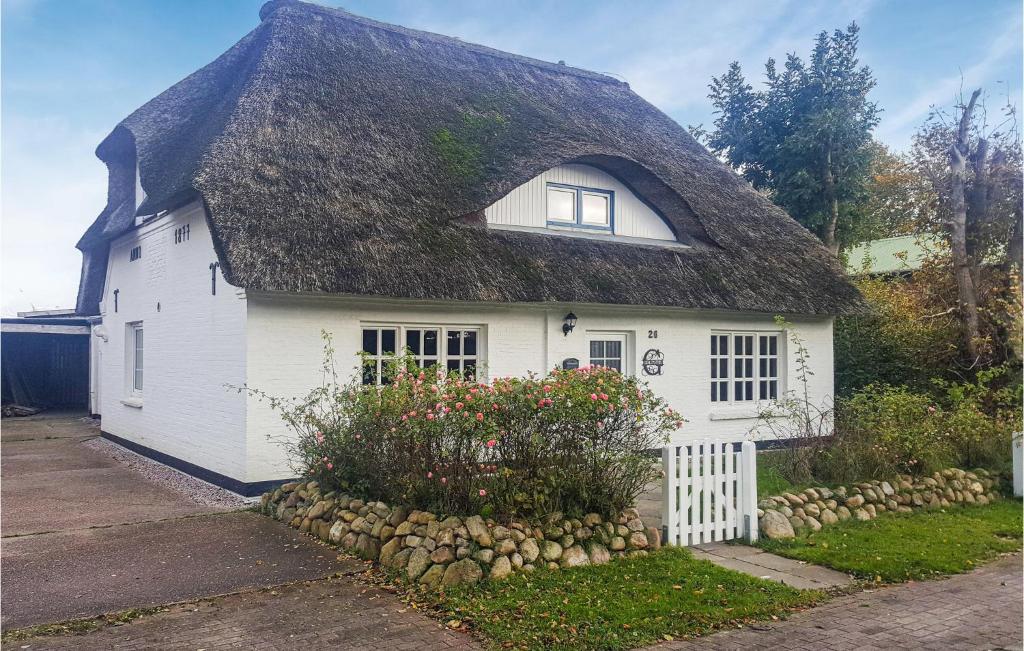 una casa bianca con tetto di paglia di Beautiful Home In Norddeich With Kitchen a Norddeich