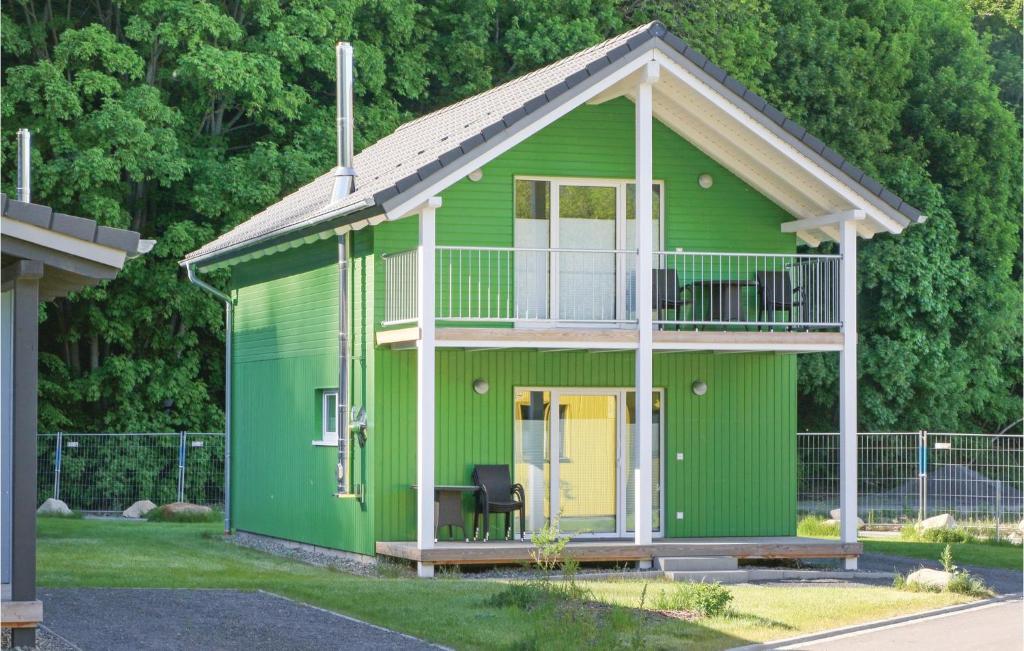 a green house with a yellow door and a balcony at Ferienhausdorf Thale in Thale