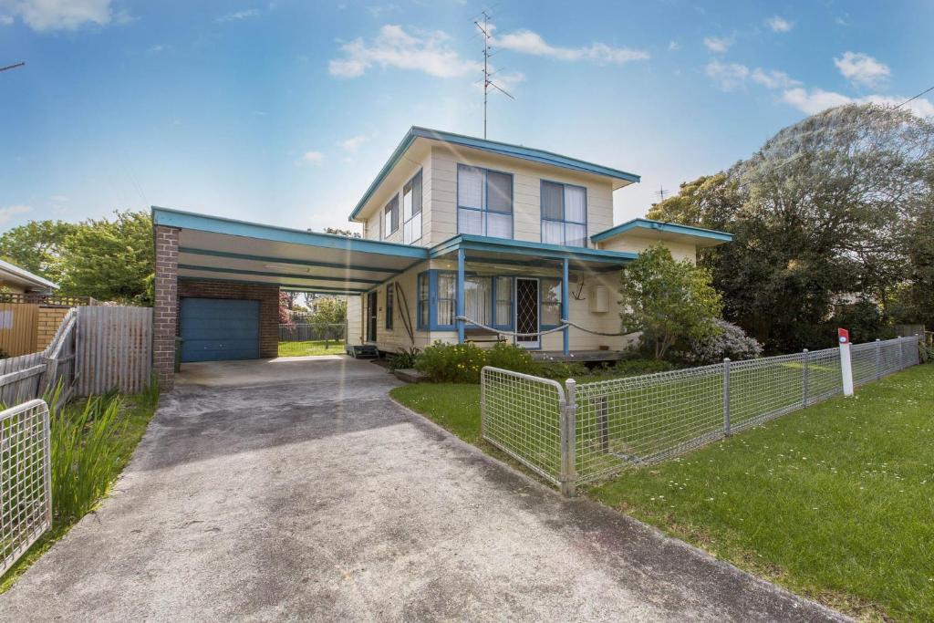 a house with a fence in front of a driveway at Holiday on Nautilus Inverloch in Inverloch