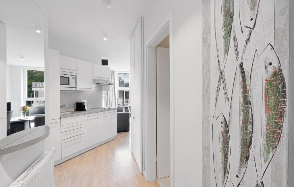 a kitchen with white cabinets and a painting on the wall at Dnenvilla Deluxe in Travemünde