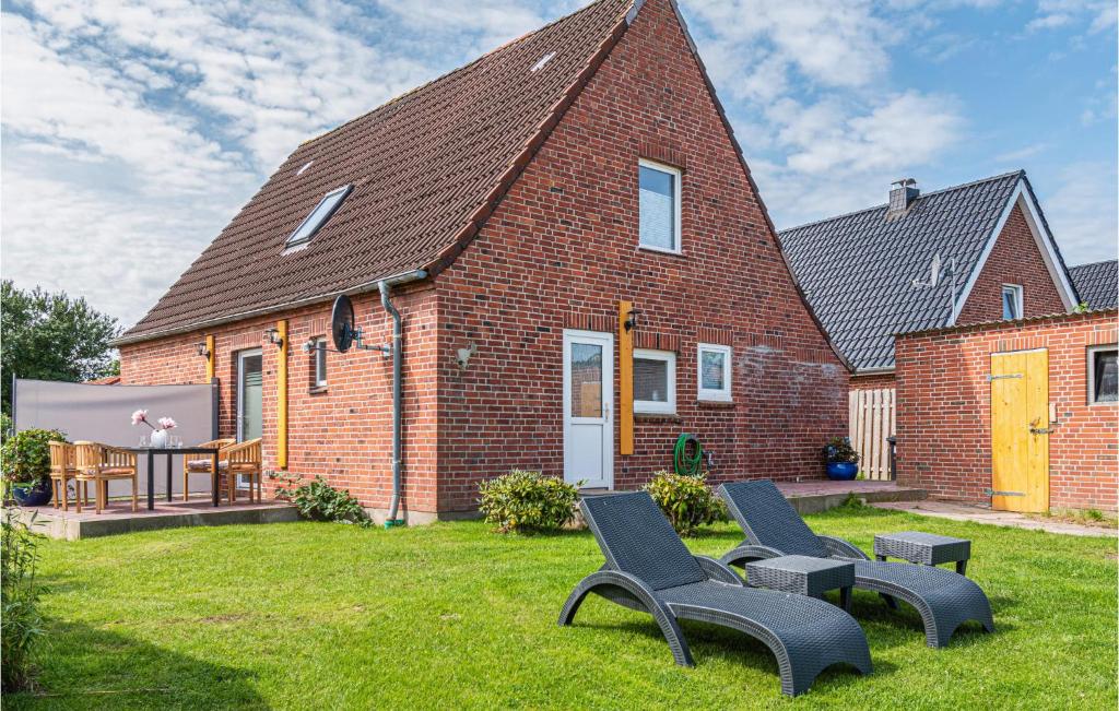 a brick house with two chairs in the yard at 3 Bedroom Cozy Home In Friedrichskoog in Friedrichskoog