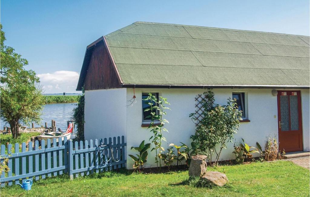 a small white house with a fence next to the water at Nice Home In Usedom With Kitchen in Wilhelmshof