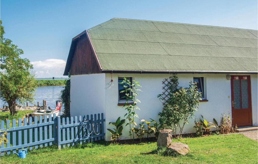 una piccola casa bianca con una recinzione vicino all'acqua di Nice Home In Usedom With Kitchen a Wilhelmshof