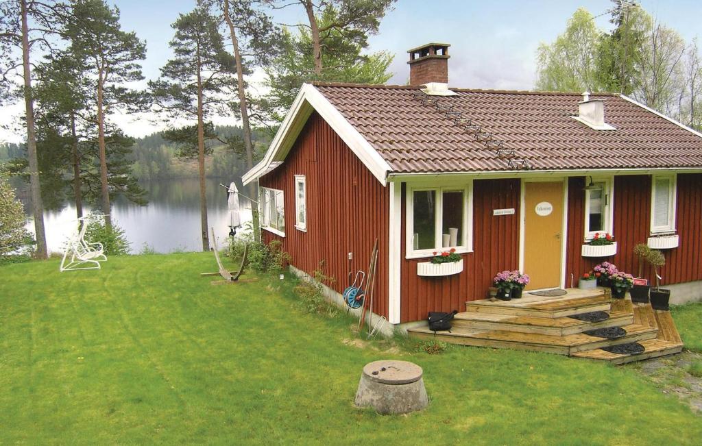 a small red house with a deck next to a lake at Beautiful Home In Aplared With 2 Bedrooms, Sauna And Wifi in Aplared