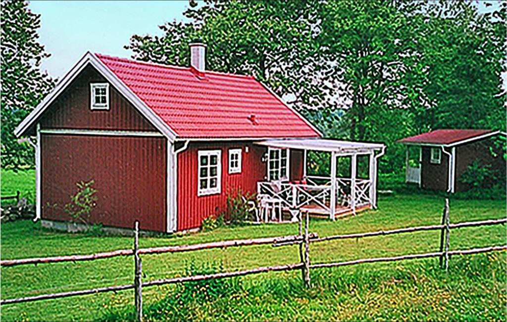 Gorgeous Home In Svsj With Kitchen في Sävsjö: منزل احمر مع شرفة بجانب سياج