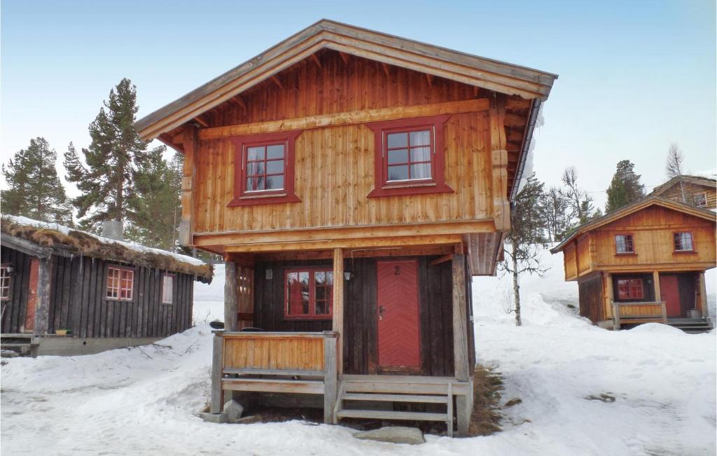 une cabane en bois avec des portes rouges dans la neige dans l'établissement Cozy Home In Ringebu With Kitchen, à Ringebu