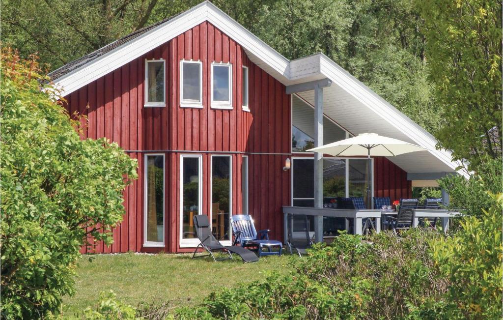 a red house with a table and an umbrella at 3 Bedroom Gorgeous Home In Rechlin in Rechlin