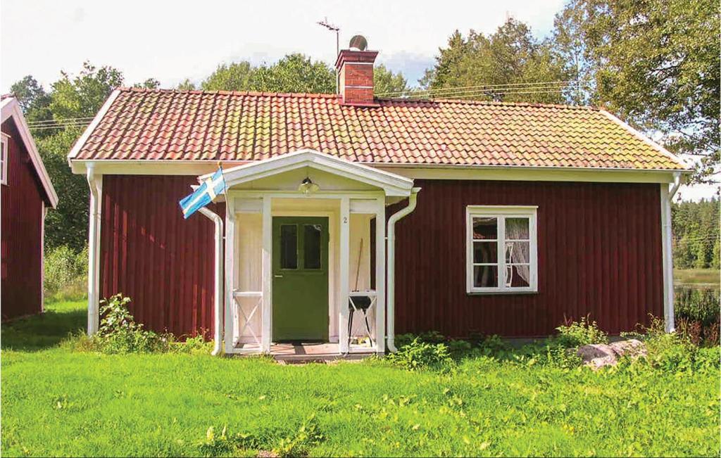 a small red house with a green door in a field at Amazing Home In Vimmerby With Wifi in Vimmerby