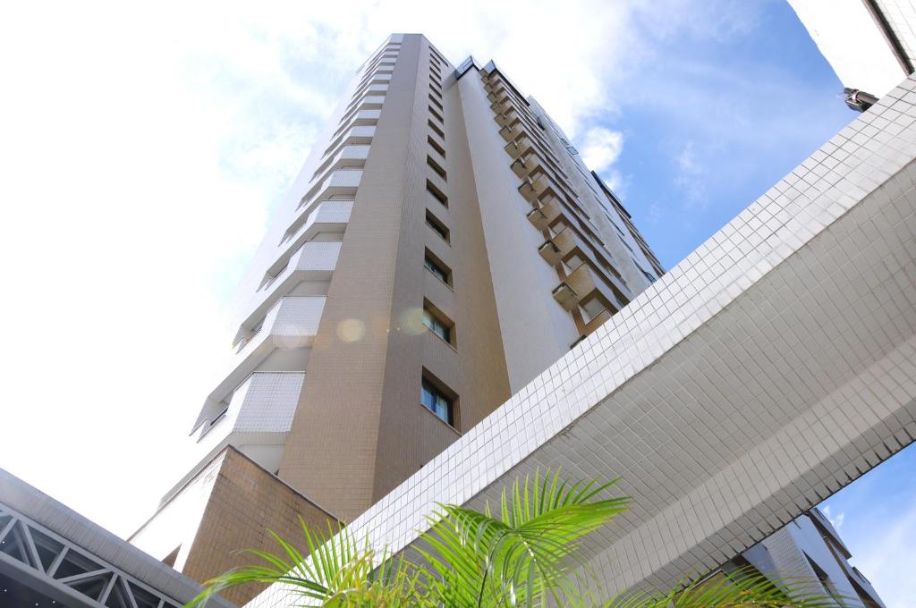 un edificio alto y blanco con palmeras delante en Brasília Santana Gold Flat, en São Paulo