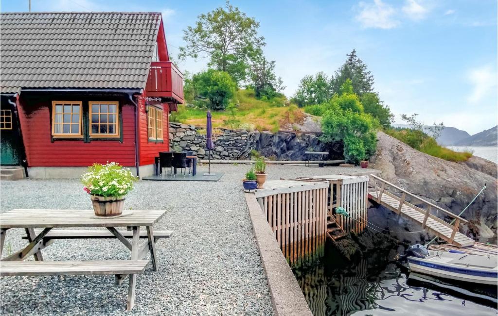 a red house with a picnic table next to the water at 2 Bedroom Lovely Home In Hyllestad in Hovland