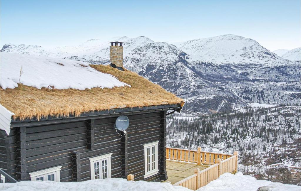 Stunning Home In Hemsedal With House Sea View في هيمسيدال: كابينة خشبية في الثلج مع جبال في الخلفية