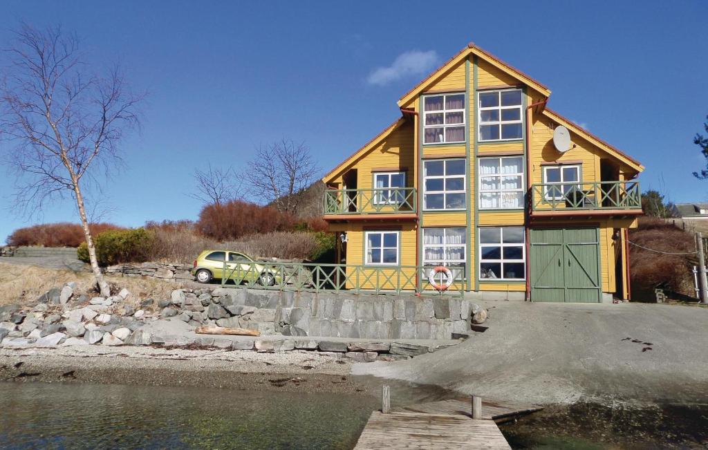 a yellow house on the shore of a body of water at Amazing Apartment In Rosendal With Sauna in Rosendal