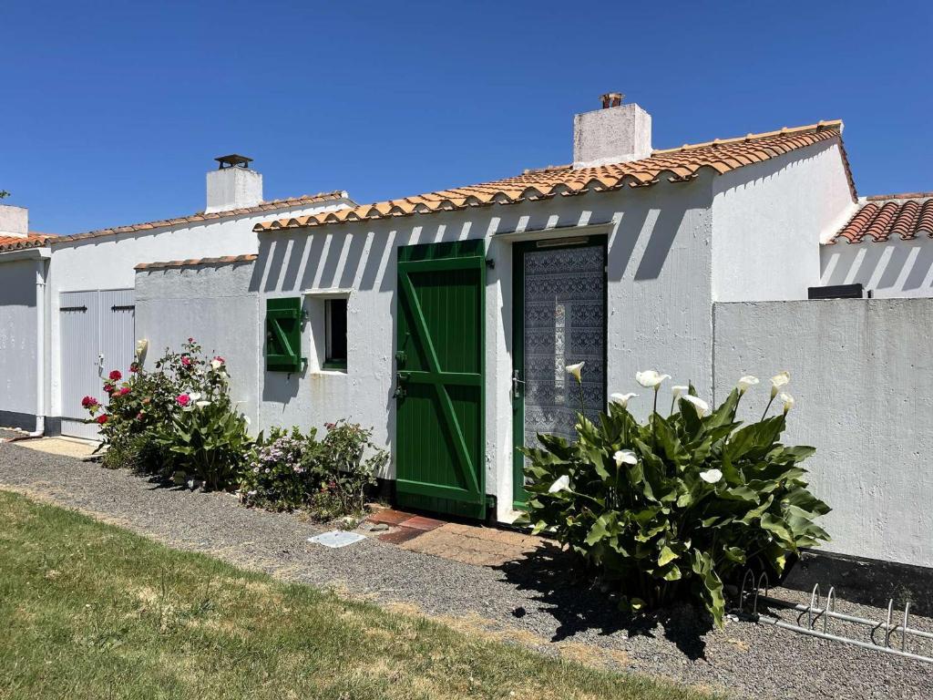 une maison blanche avec une porte verte et quelques plantes dans l'établissement Maison Bretignolles-sur-Mer, 2 pièces, 4 personnes - FR-1-224A-56, à Bretignolles-sur-Mer