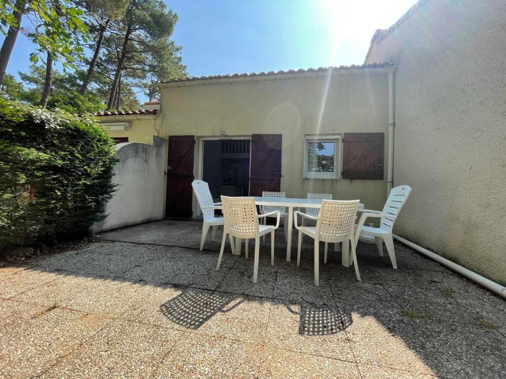 un patio avec une table et des chaises devant un bâtiment dans l'établissement Charmante maisonnette proche centre et plage, terrasse, parking et à 1km des plages ! - FR-1-550-41, aux Mathes