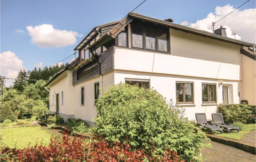 a white house with two chairs in a yard at Stunning Apartment In Duppach With Kitchen in Duppach