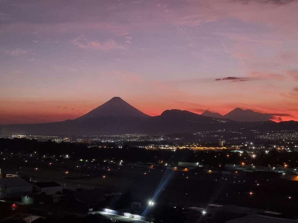 a view of a city and mountains at sunset at Amazing Volcano Views in front of airport in Guatemala