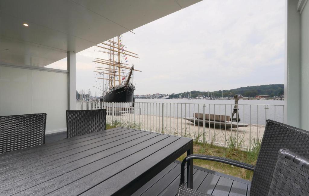 a porch with a wooden table and a boat on the water at Promenadenvilla in Priwall