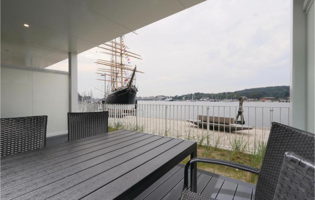 a porch with a wooden table and a boat on the water at Priwallpromenade 3, Whg 2 in Priwall