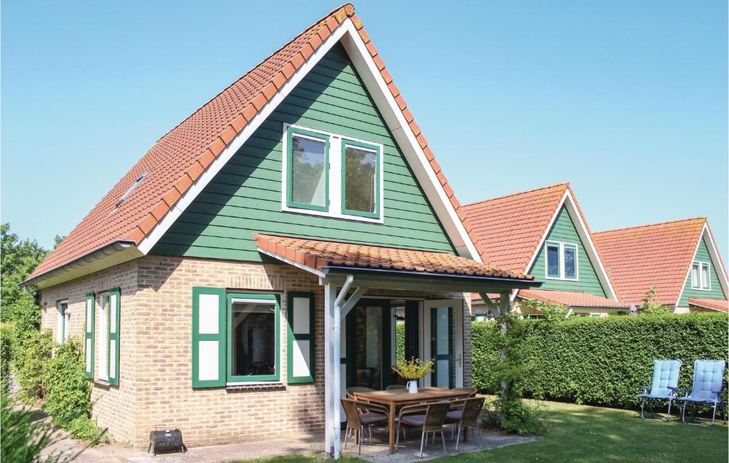 een huis met een groen dak en een tafel bij 3 Bedroom Awesome Home In Zonnemaire in Zonnemaire