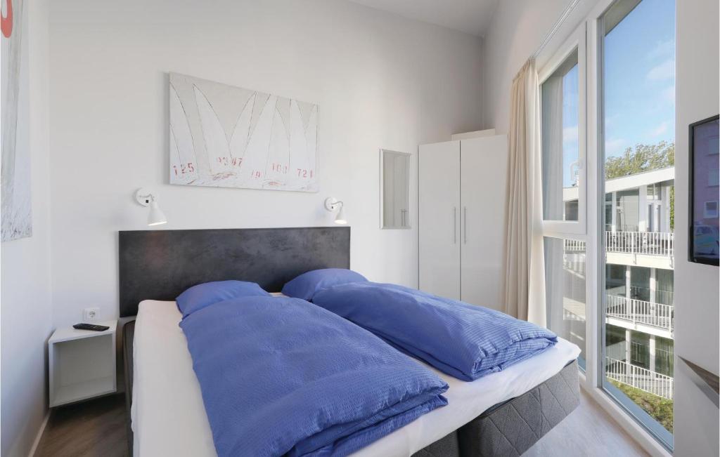 ein Schlafzimmer mit einem Bett mit blauen Kissen und einem Fenster in der Unterkunft Dnenvilla Penthouse Superior in Travemünde
