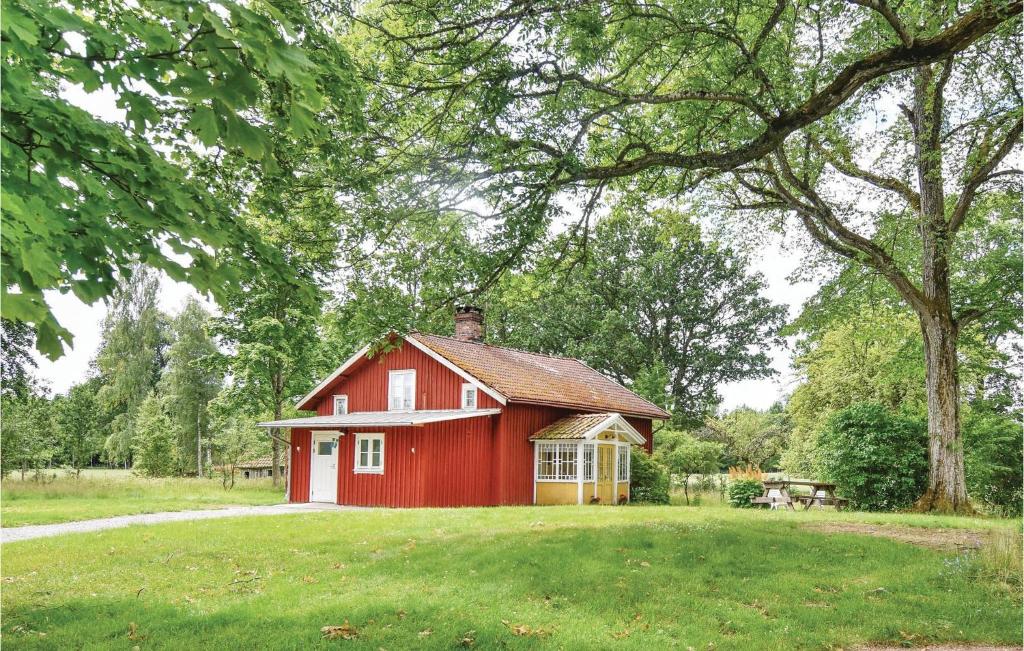 a red house in a field with a tree at Holiday Home Bön Granbacken Brålanda in Sörbo