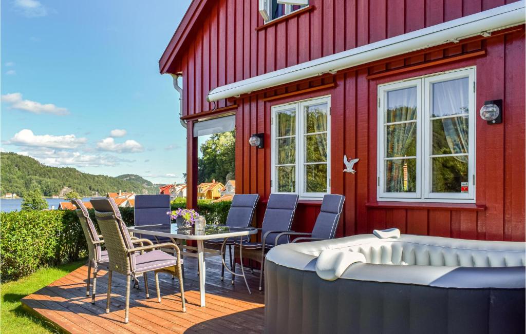 a red house with a table and chairs on a deck at Beautiful Home In Risør With Kitchen in Songe