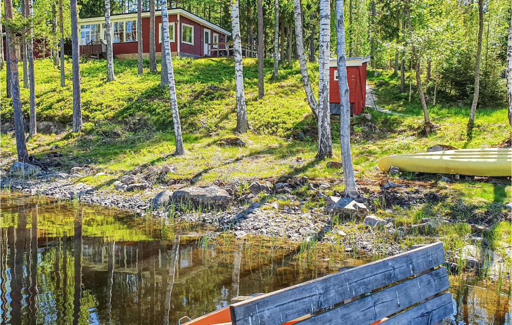 a house in the woods next to a body of water at Beautiful Home In Svanskog With 2 Bedrooms And Sauna in Slirud