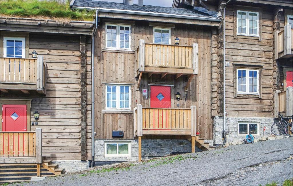 a log cabin with red doors and a deck at Sjusjøen Setergrend 4763 in Sjusjøen