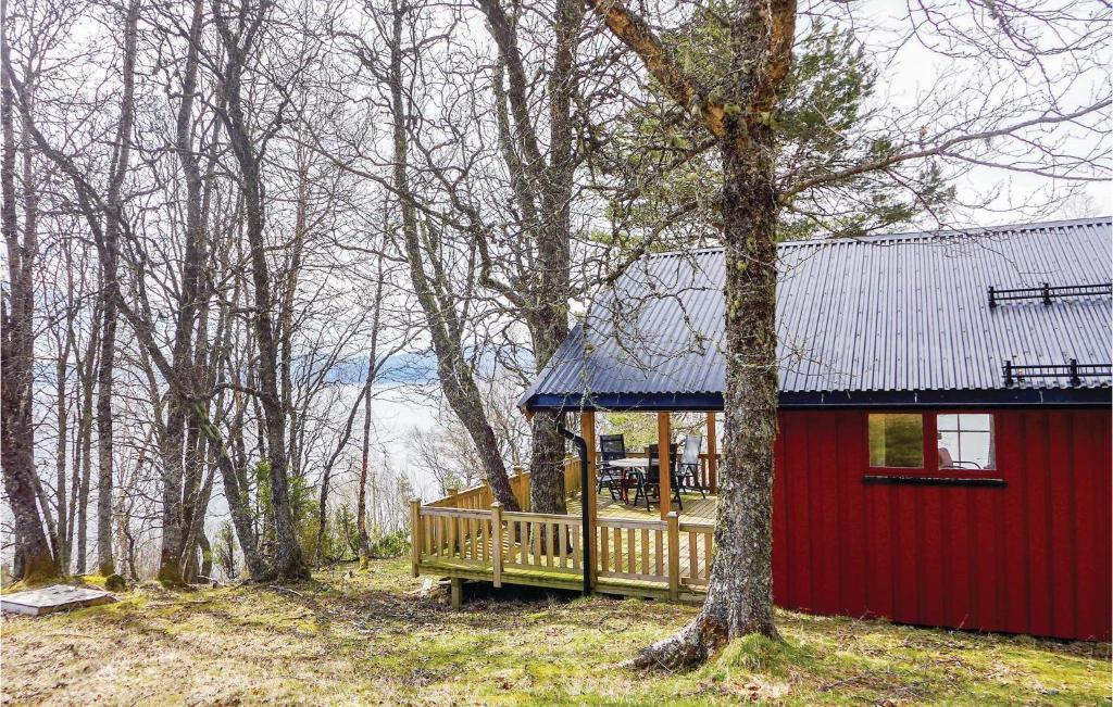 una cabaña roja en el bosque con un árbol en Bjrgan Grd en Vannvikan