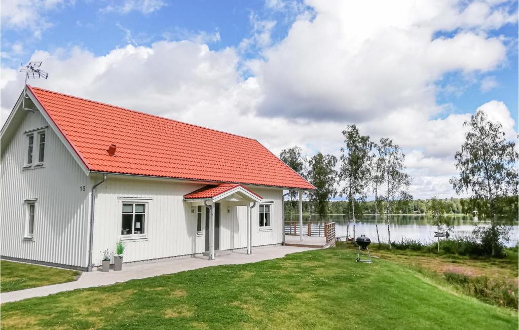 a white house with an orange roof next to a lake at Beautiful Home In Skillingaryd With Wifi in Skillingaryd