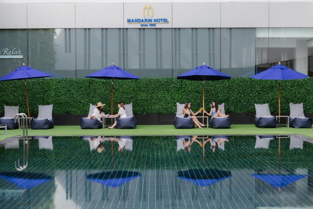 a group of people sitting on a couch next to a pool at Mandarin Hotel Managed by Centre Point in Bangkok