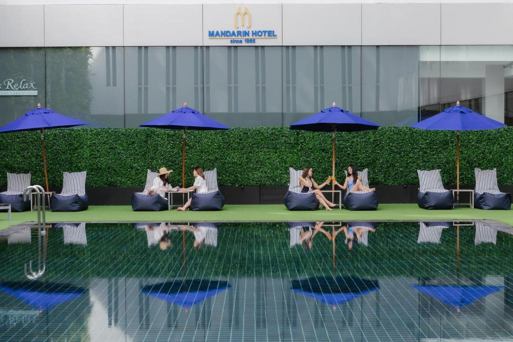 un grupo de personas sentadas en un sofá junto a una piscina en Mandarin Hotel Managed by Centre Point, en Bangkok