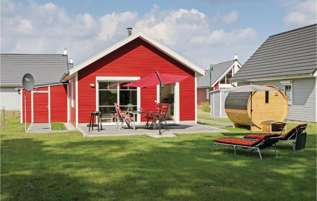 a red house with a table and chairs in a yard at Cozy Home In Zerpenschleuse With Sauna in Zerpenschleuse