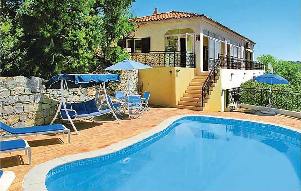 a swimming pool with chairs and umbrellas in front of a house at Amazing Home In S,brs De Alportel With Kitchen in Almargens