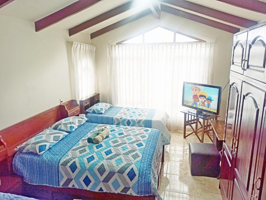 1 Schlafzimmer mit 2 Betten und einem Flachbild-TV in der Unterkunft Residencial Moroni - Alojamiento en Cochabamba in Cochabamba