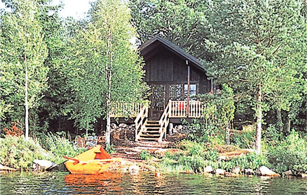 a cabin on a lake with a boat in front of it at Sjöstugan in Pålsmåla